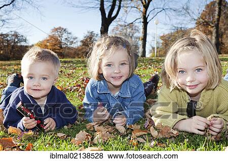 Boy, 2, with his sisters, 4 and 6, in a park in autumn View Large Photo Image Stock Photo - Boy, 2, with his sisters, 4 and 6, in a park in autumn. Fotosearch