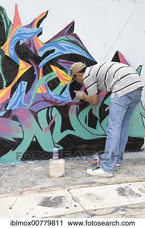 Stock Image - Boy spraying graffiti on a wall in Singapore, Southeast Asia. Fotosearch
