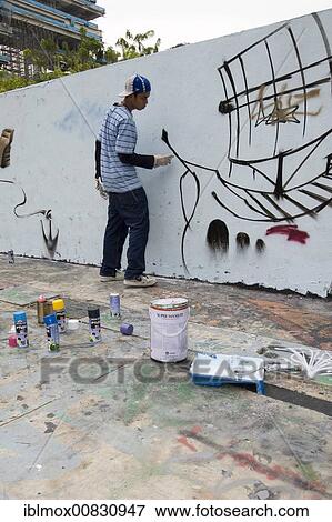 Stock Photo - Boy spraying graffiti on a wall in Singapore, Southeast Asia. Fotosearch