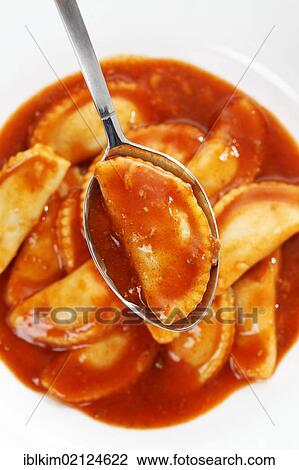 Stock Image - Canned ravioli on a white plate and spoon. Fotosearch