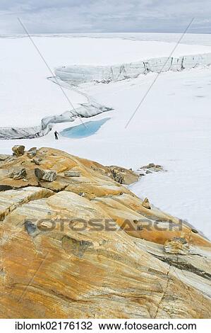 Stock Image - Coloured rock structures, hiker at Mittivakkat Glacier, Peninsula Ammassalik, East Greenland, Greenland, North America. Fotosearch