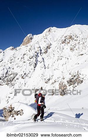 Stock Photo - Cross-country skier above Woerndle-Loch-Alm alpine pasture while ascending Zendleser Kofel Mountain in the Villnoess Valley above Zanser Alm alpine pasture in front of Aferer Geisler Mountain, Alto Adige, Italy, Europe. Fotosearch