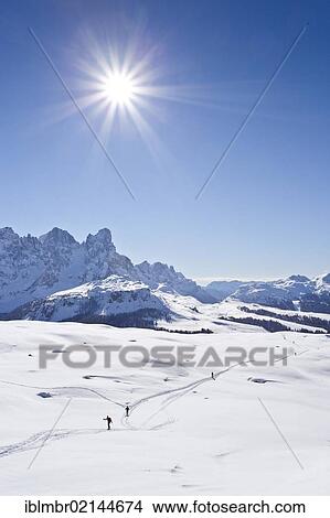 Picture - Cross-country skiers ascending Cima Bocche Mountain above Passo Valles Pass, overlooking the Palla Group beside Passo Rolle Pass, Dolomites, Trentino, Italy, Europe. Fotosearch
