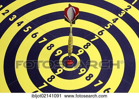 Stock Image - Darts, throwing game, dart sticking into the middle of the dartboard, the bullseye. Fotosearch