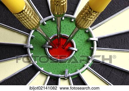 Stock Image - Darts, throwing game, darts sticking into the middle of the dartboard, the bullseye. Fotosearch