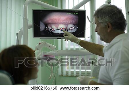 Dentist explaining to patient how a brace functions View Large Photo Image Stock Image - Dentist explaining to patient how a brace functions. Fotosearch