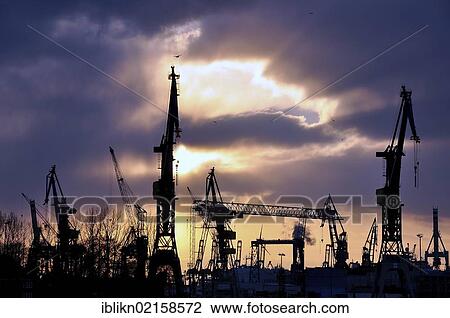 Stock Image - Dockside cranes in front of the evening sky, Port of Hamburg, Hamburg, Germany, Europe. Fotosearch