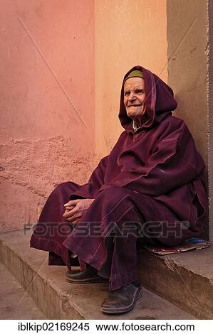 Stock Photography - Elderly man wearing a robe sitting on steps in Marrakesh, Morocco, Africa. Fotosearch