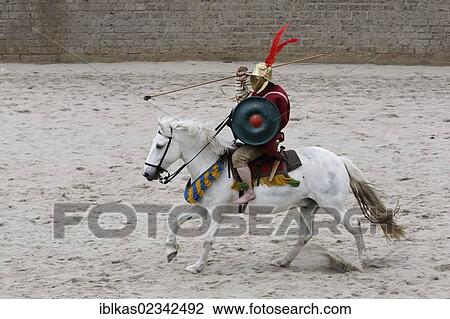 Stock Image - Eques, a gladiator on horseback, gladiator fight, exhibition fight, Familia Gladiatoria Pulli Cornicinis by Marcus Junkelmann, Roemerfest festival 2012, stadium of the Archaeologischer Park Xanten outdoor museum, Lower Rhine region, North.... Fotosearch