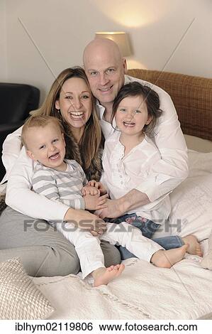 Family with two children on a double bed View Large Photo Image Stock Photograph - Family with two children on a double bed. Fotosearch