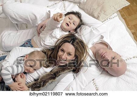 Stock Photo - Family with two children playing on a double bed. Fotosearch