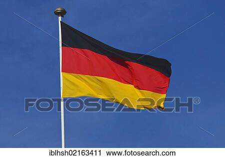 Stock Image - German national flag against a blue sky. Fotosearch