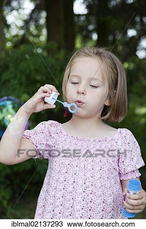 Stock Image - Girl, 4, blowing soap bubbles. Fotosearch