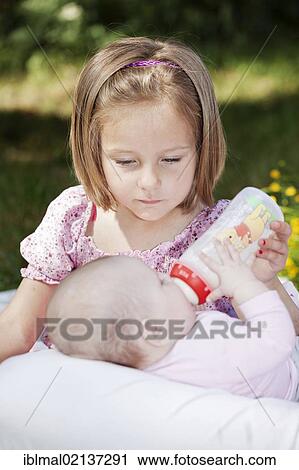 Girl, 4, feeding a baby with a bottle View Large Photo Image Stock Image - Girl, 4, feeding a baby with a bottle. Fotosearch