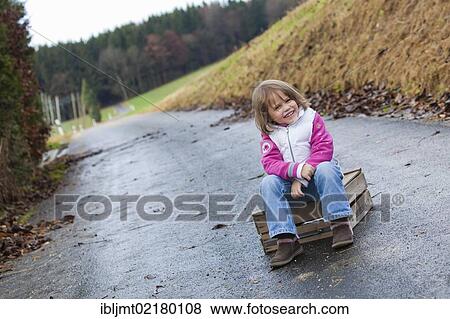 Stock Photo - Girl, 4, sitting on a wooden crate on a path. Fotosearch