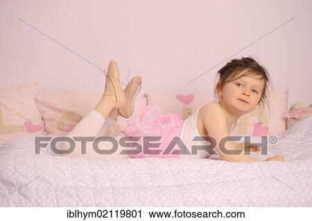 Stock Image - Girl, 5, wearing a ballet outfit on her bed. Fotosearch