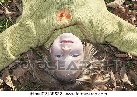 Girl, 6, lying on the ground in the foliage in autumn View Large Photo Image Stock Image - Girl, 6, lying on the ground in the foliage in autumn. Fotosearch