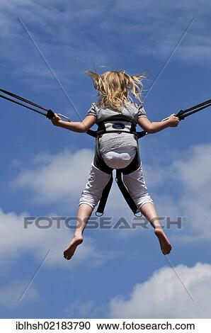 Girl jumping on a trampoline with a safety harness, back side, North Rhine-Westphalia, Germany, Europe View Large Photo Image Stock Image - Girl jumping on a trampoline with a safety harness, back side, North Rhine-Westphalia, Germany, Europe. Fotosearch