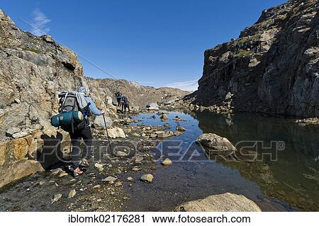 Stock Image - Group of hikers with backpacks, Ammassalik Peninsula, East Greenland, Greenland, North America. Fotosearch