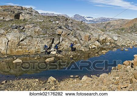 Stock Image - Group of hikers with backpacks, Ammassalik Peninsula, East Greenland, Greenland, North America. Fotosearch