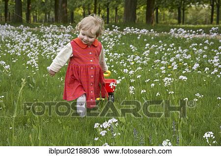 Stock Photograph - Happy little girl walking on a meadow. Fotosearch