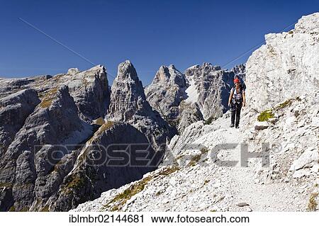 Stock Image - Hiker ascending the Alpinisteig climbing route on Einser Mountain, looking towards Dreischusterspitze Mountain, Sesto, Alta Pusteria, Dolomites, Alto Adige, Italy, Europe. Fotosearch