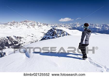Stock Image - Hiker on Cima Bocche Mountain above Passo Valles, overlooking Uribrutto Mountain, the Marmolada South Face and Pelmo Mountain, Trentino, Dolomites, Italy, Europe. Fotosearch
