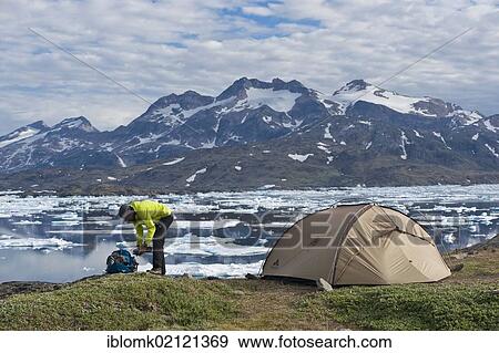 Stock Photo - Hiker, tent, ice floes and mountains, Tasiilaq or Ammassalik, East Greenland. Fotosearch