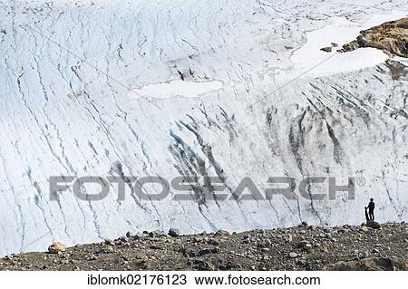 Stock Image - Hiker with a rifle, at Mittivakkat Glacier, Ammassalik Peninsula, East Greenland, Greenland, North America. Fotosearch