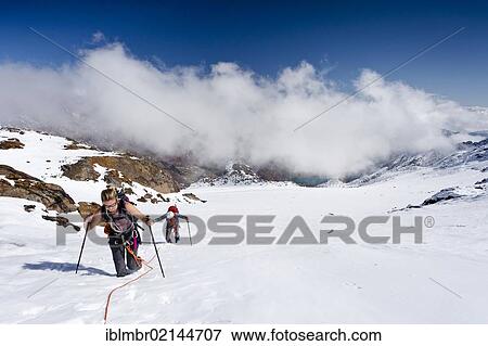 Stock Photo - Hikers ascending Hintere Eggenspitze Mountain in Ulten Valley above Gruensee Lake, on Weissbrunnferner Mountain overlooking Gruensee Lake, Alto Adige, Italy, Europe. Fotosearch