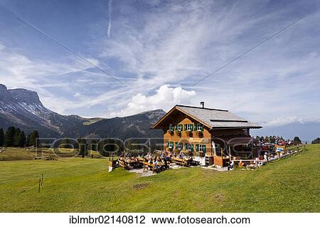Stock Image - Hikers at the Gschnagenhardt Alm in Villnoess valley below the Odle, behind the Seceda and Rasciesa, Dolomites, South Tyrol, Italy, Europe. Fotosearch