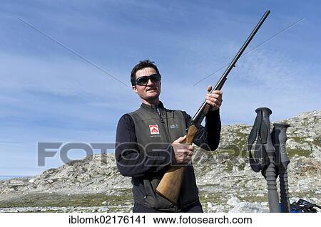 Stock Image - Hiking guide holding a rifle, polar bear protection, Ammassalik Peninsula, Sermilik Fjord, East Greenland, Greenland, North America. Fotosearch