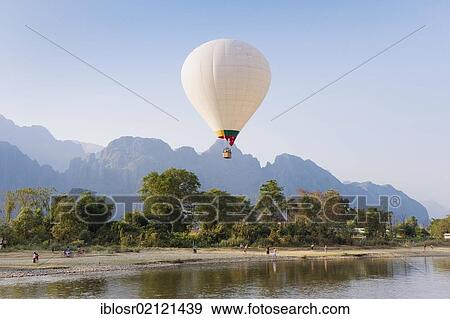 Hot air balloon flying over the karst mountains at the Nam Song River, Vang Vieng, Vientiane, Laos, Indochina, Asia View Large Photo Image Stock Photo - Hot air balloon flying over the karst mountains at the Nam Song River, Vang Vieng, Vientiane, Laos, Indochina, Asia. Fotosearch
