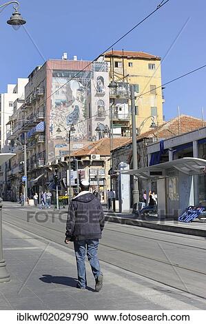 Stock Image - Jew wearing a kippah or a yarmulke, rails of the new tram line and a mural on a building showing the new tram, Jaffa Road, Jerusalem, Israel, Middle East, Asia. Fotosearch