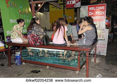 Stock Photo - Khmer women getting a foot massage from doctor fish at the roadside, Siem Reap, Cambodia, Southeast Asia, Asia. Fotosearch