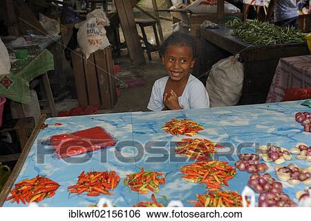 Stock Photograph - Little Papuan girl selling chili peppers and onions at the market, Kota Biak, Biak Island, Irian Jaya, Indonesia, Southeast Asia, Asia. Fotosearch