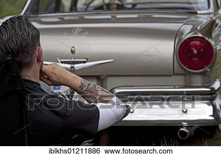 Man sitting in front of the rear of his vintage car View Large Photo Image Stock Photograph - Man sitting in front of the rear of his vintage car. Fotosearch