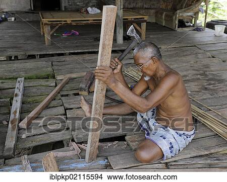 Picture - Man working with a hatched on a piece of wood, Koh Lanta, Thailand, Asia. Fotosearch