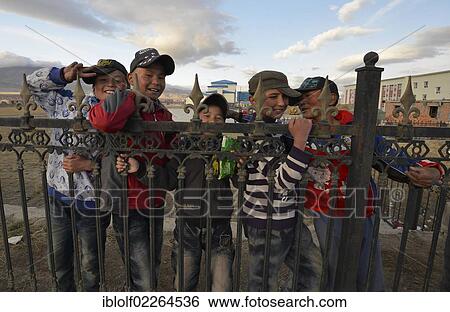 Stock Photograph - Mongolian boys with baseball caps standing behind a fence of a school, Bayanbulak, Bayingolin Mongol Autonomous Prefecture, Kuqa, Silk Road, Tianshan Mountains, Tien Shan, Xinjiang, China, Asia. Fotosearch