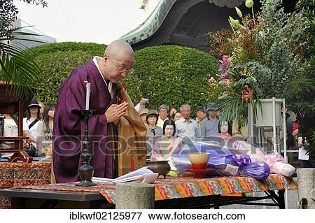 Stock Photo - Nun praying at the alter over a pile of dolls for a Buddhist memorial service, so that the souls of the dolls can be redeemed, Hokyo-ji Temple, Kyoto, Japan, East Asia, Asia. Fotosearch