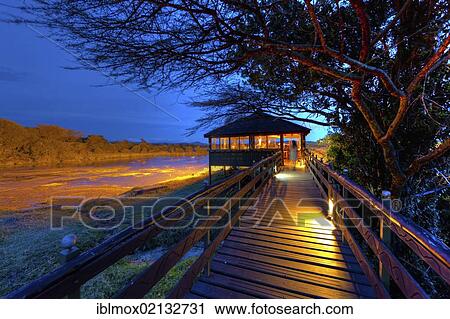 Stock Image - Observation point at a waterhole at dusk, Keekorok Lodge, Masai Mara National Reserve, Kenya, East Africa, Africa. Fotosearch