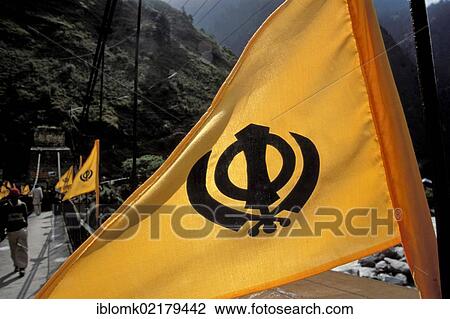 Stock Image - Orange flag with a Khanda symbol, religious emblem for the Sikhs and Sikhism, Govindghat, Chamoli district, Uttarakhand, formerly Uttaranchal, Indian Himalayas, North India, India, Asia. Fotosearch