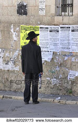 Stock Image - Orthodox Jew reading a wall newspaper in the district of Me'a She'arim or Mea Shearim, Jerusalem, Israel, Middle East, Asia. Fotosearch