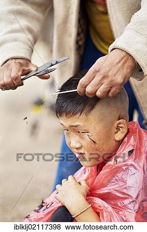 Stock Photo - Palong boy getting a haircut at the roadside in Norlae village, northern Thailand, Asia. Fotosearch