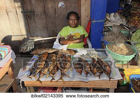 Papuan woman selling fried fish at the fish market in Kota Biak, waving the flies away with a plastic bag on a stick, Biak Island, West Papua, Indonesia, Southeast Asia, Asia View Large Photo Image Stock Photography - Papuan woman selling fried fish at the fish market in Kota Biak, waving the flies away with a plastic bag on a stick, Biak Island, West Papua, Indonesia, Southeast Asia, Asia. Fotosearch