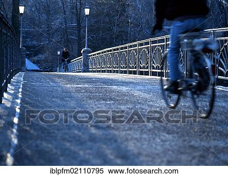 Stock Photography - People riding bicycles across the Zenneck Bridge on an early cold winter morning, Munich, Upper Bavaria, Germany, Europe. Fotosearch