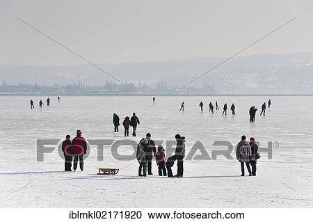 Stock Image - People walking on the ice of a frozen Lake Constance, Markelfinger Winkel, Radolfzell, Konstanz district, Baden-Wuerttemberg, Germany, Europe. Fotosearch