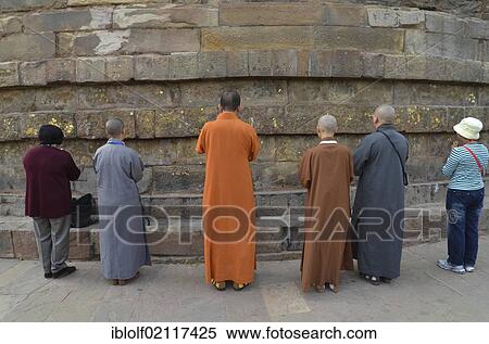 Praying Buddhist monks and believers in different orange and gray robes, pilgrims, men and women from various Buddhist schools and traditions brought together in front of the Dhamekh Stupa, Deer Park of Isipatana, Sarnath, Uttar Pradesh, India, South... View Large Photo Image Stock Photography - Praying Buddhist monks and believers in different orange and gray robes, pilgrims, men and women from various Buddhist schools and traditions brought together in front of the Dhamekh Stupa, Deer Park of Isipatana, Sarnath, Uttar Pradesh, India, South.... Fotosearch