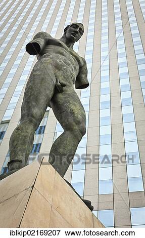 Stock Photo - Sculpture of a man in front of a glass building in the business district of La Défense, Paris, France, Europe. Fotosearch