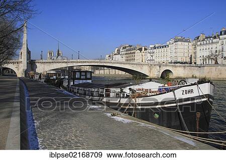 Stock Photo - Seine river with the bridge Pont La Tournelle and a cargo ship, Notre-Dame, Paris, France, Europe. Fotosearch